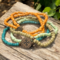 This handmade stretch bracelet is in colors of pale green, orange and beige . There are 5 bracelets in this stack.